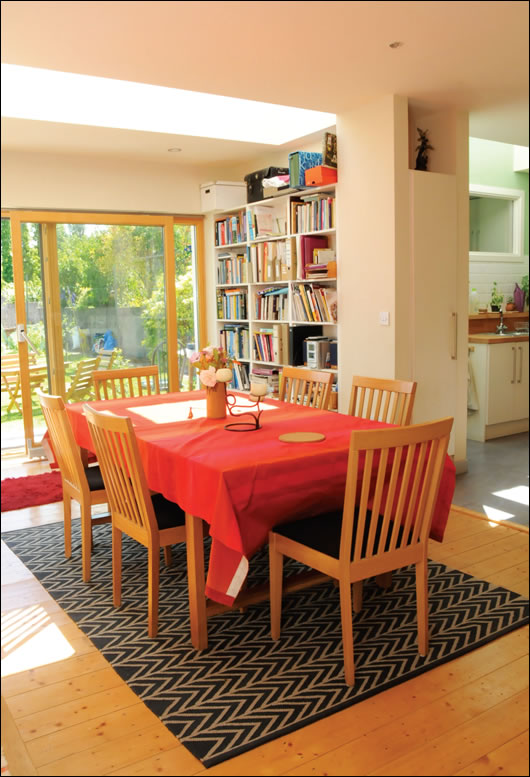 The design creates an open plan kitchen/dining room with visual connection to the garden through the extension at the rear of the house, while the triple-glazed sliding door and row of rooflights let plenty of natural light in