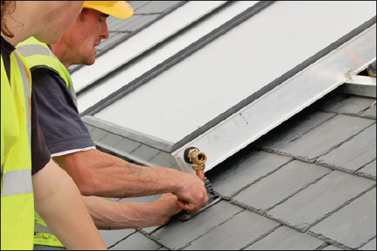 A flat plate solar collector being installed A flat plate solar collector being installed